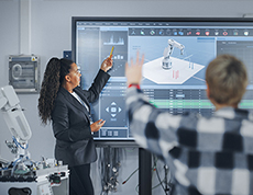 A teacher at a overhead screen looking a robotics projects