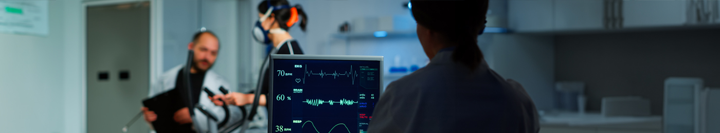 Medical researcher examining EKG image showing on monitor while patient with mask running