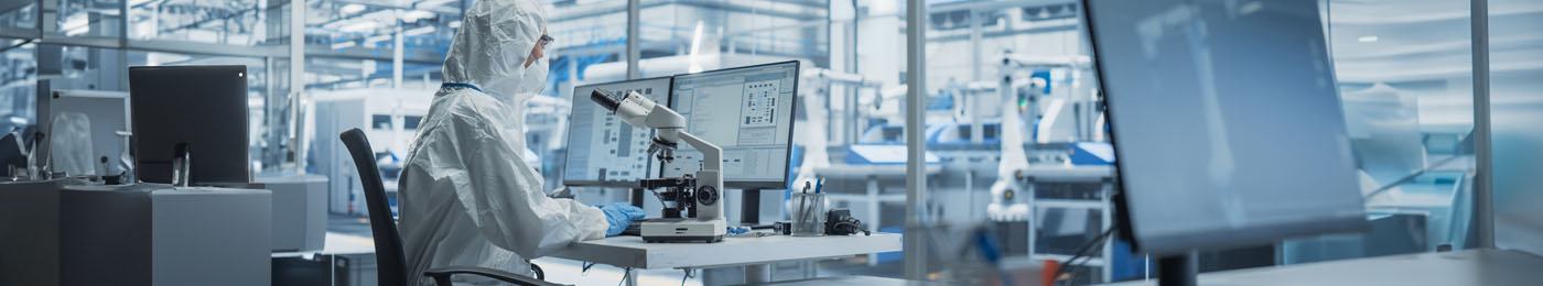 Industrial Engineer Working on Desktop Computer in Clean Sterile Coveralls